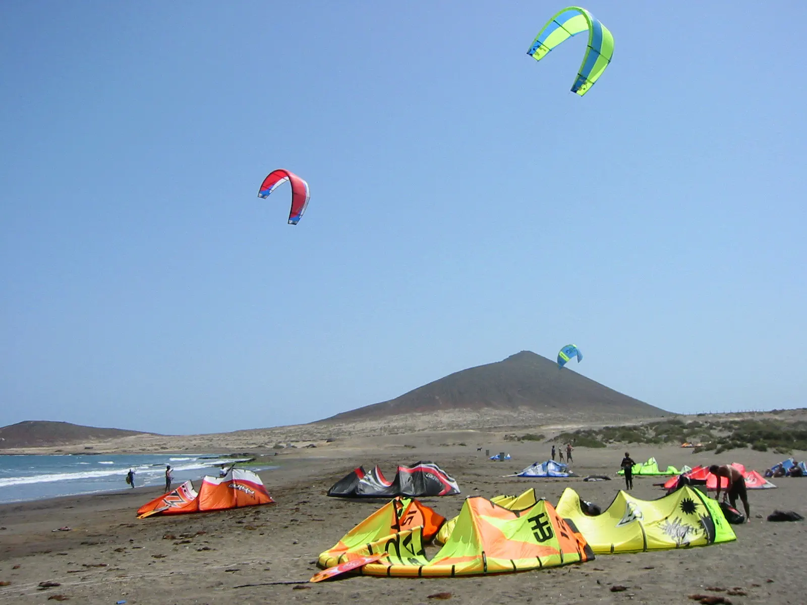 Kitesurf-Drachen über dem Strand von El Médano mit Montaña Roja im Hintergrund.