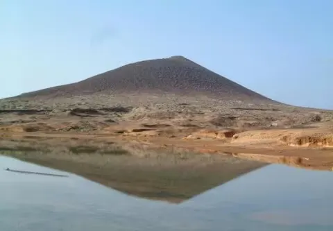 Montaña Roja spiegelt sich im Wasser am Ufer von El Médano.