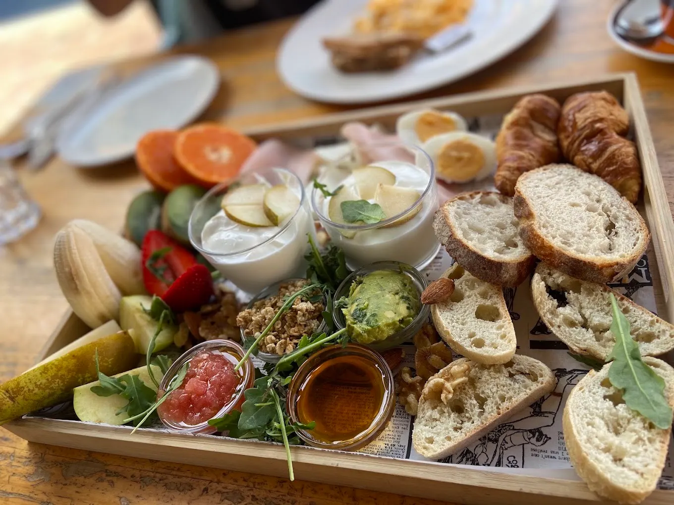 Frühstückstablett mit Brot, Obst, Joghurt und Gebäck im Veinte 04 Surf Café.