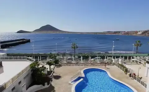 Blick von der gemeinschaftlichen Dachterrasse des Gebäudes über den Pool, das Meer und Montaña Roja.