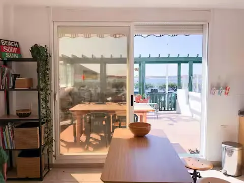 Blick vom Wohnzimmer durch die Schiebetür auf die Terrasse und das Meer.