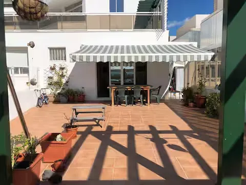 Große Terrasse mit Markise, Essplatz im Freien und einer weiteren Terrasse im Hintergrund.